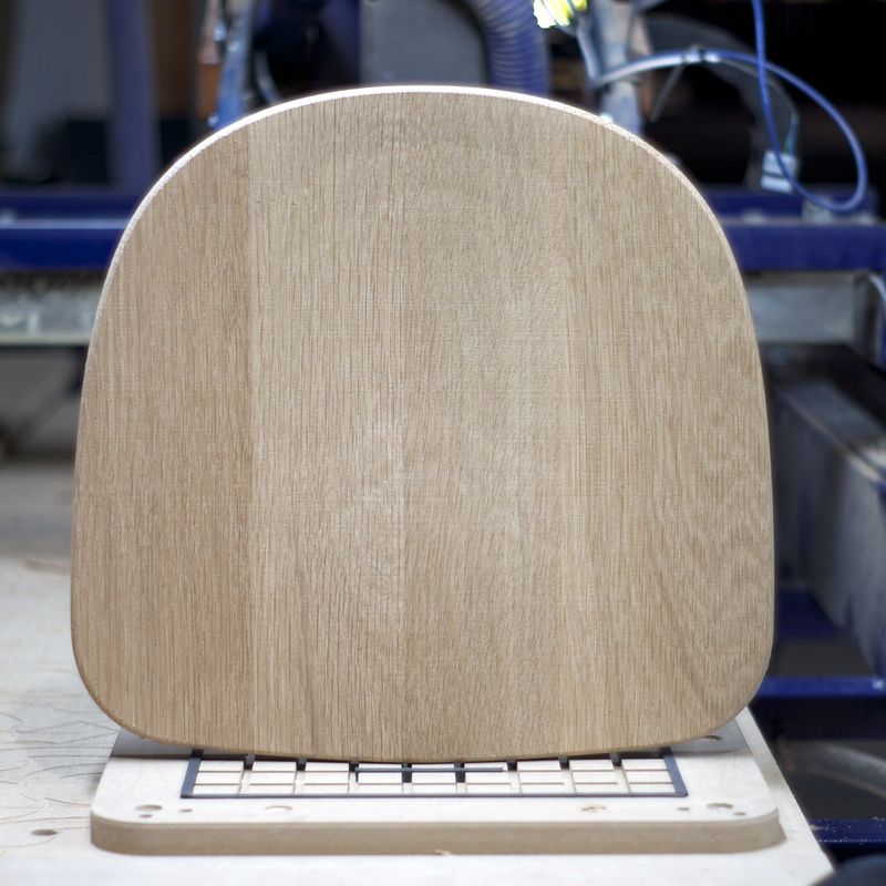 Chair seat standing up, cut while held on a vacuum hold-down